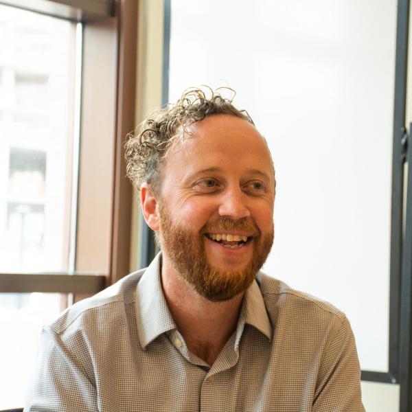 Otto Hanson smiling during a conversation by an office window