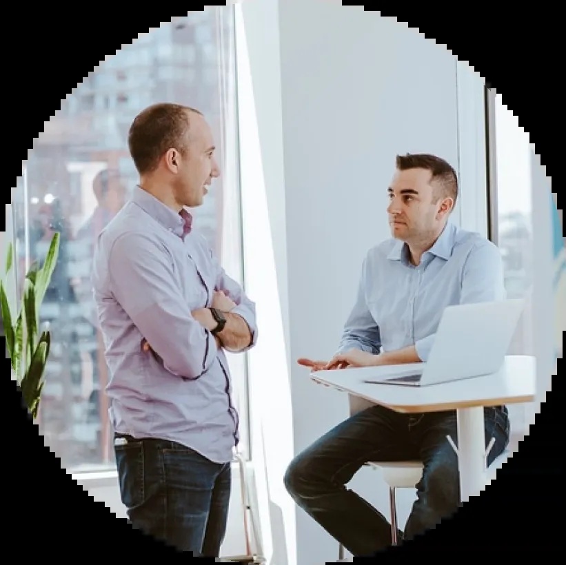 Own Up founders talking beside a laptop in a bright office