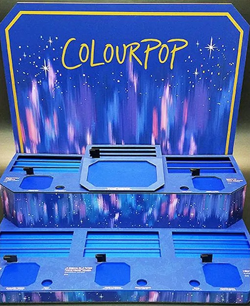 Blue ColourPop cosmetics fixture with product compartments and a decorative back panel