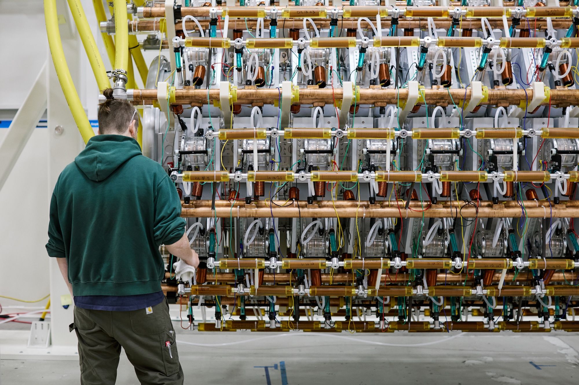 A Pacific Fusion worker beside the repeated components of its scaled pulser prototype