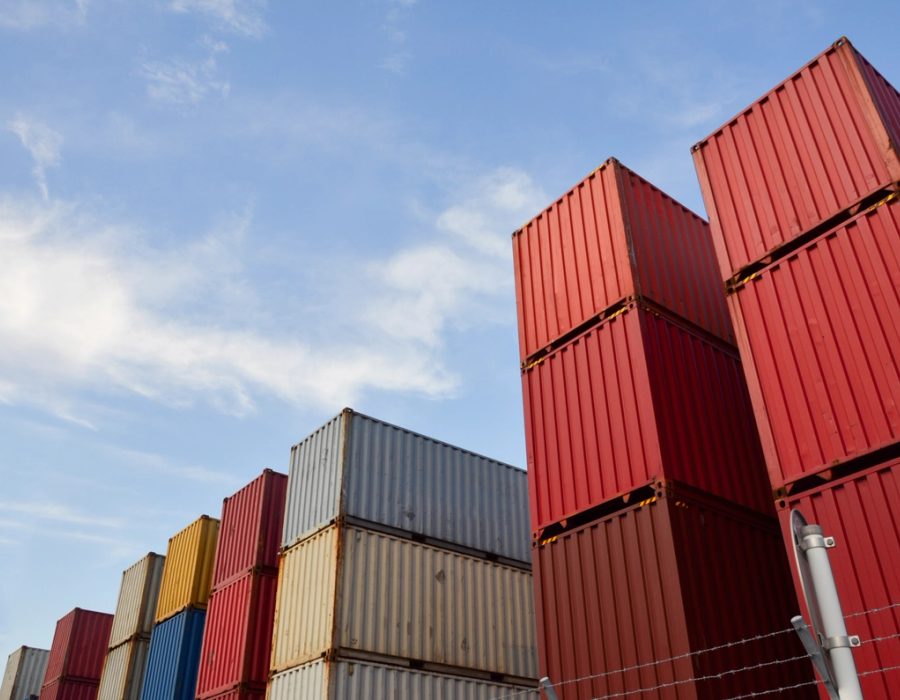 Stacks of red, blue, and gray shipping containers under an open sky