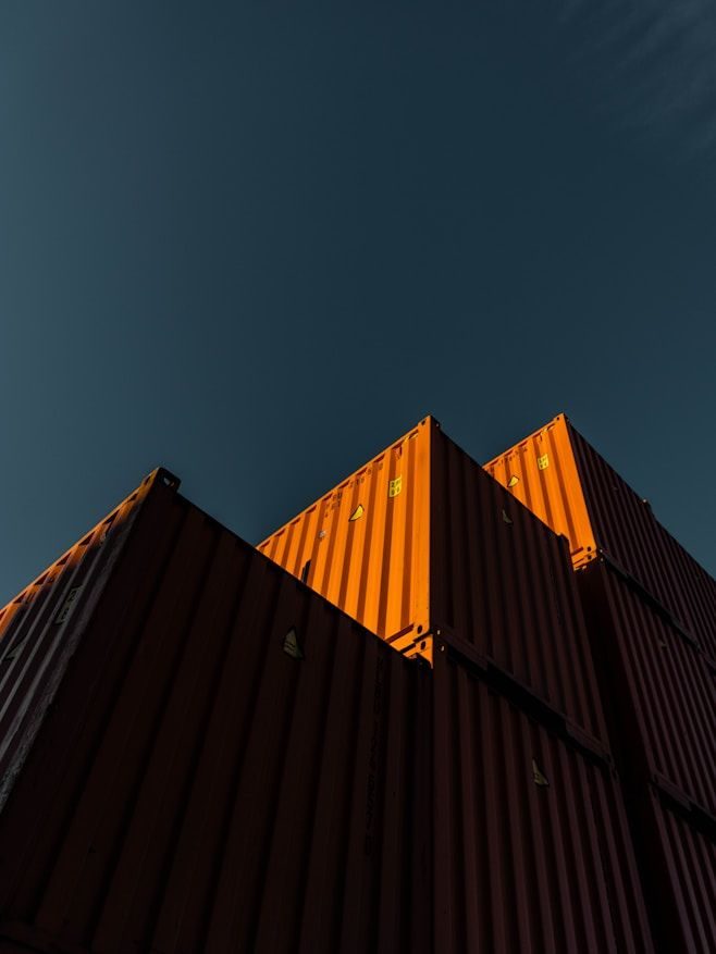 Orange shipping containers stacked against a dark blue sky