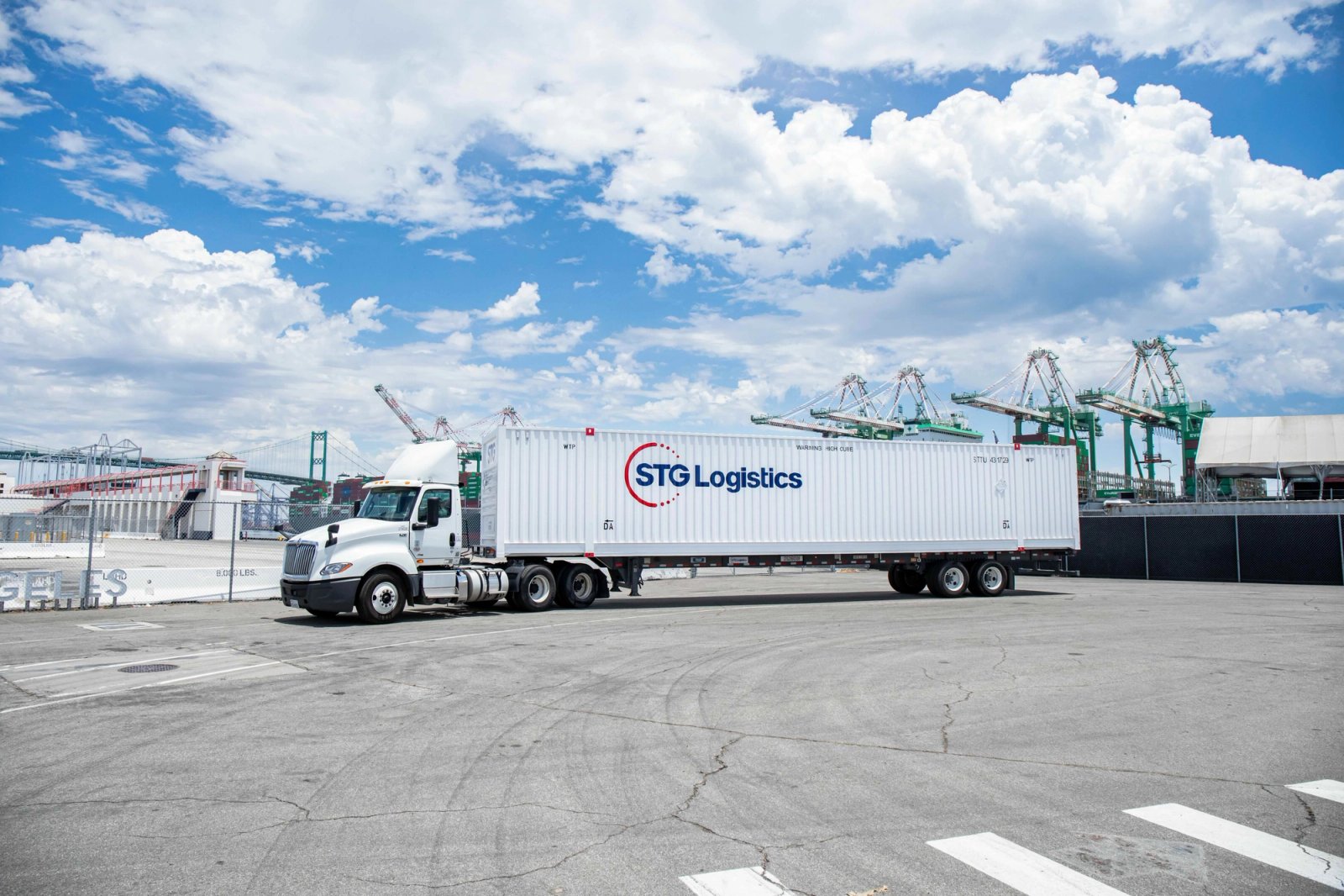 STG Logistics truck and container beside port cranes