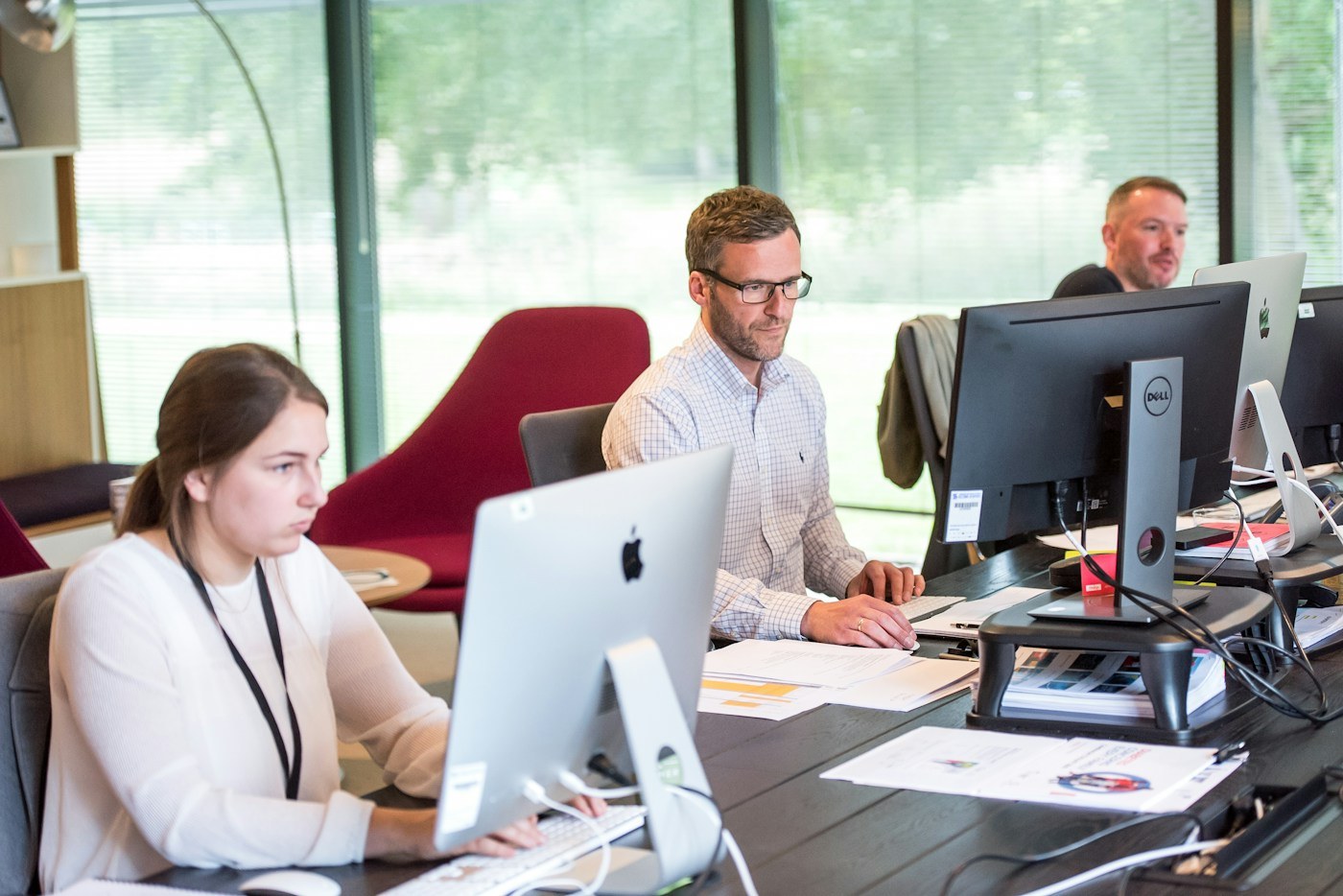 Office workers seated at desktop computers in a shared workspace