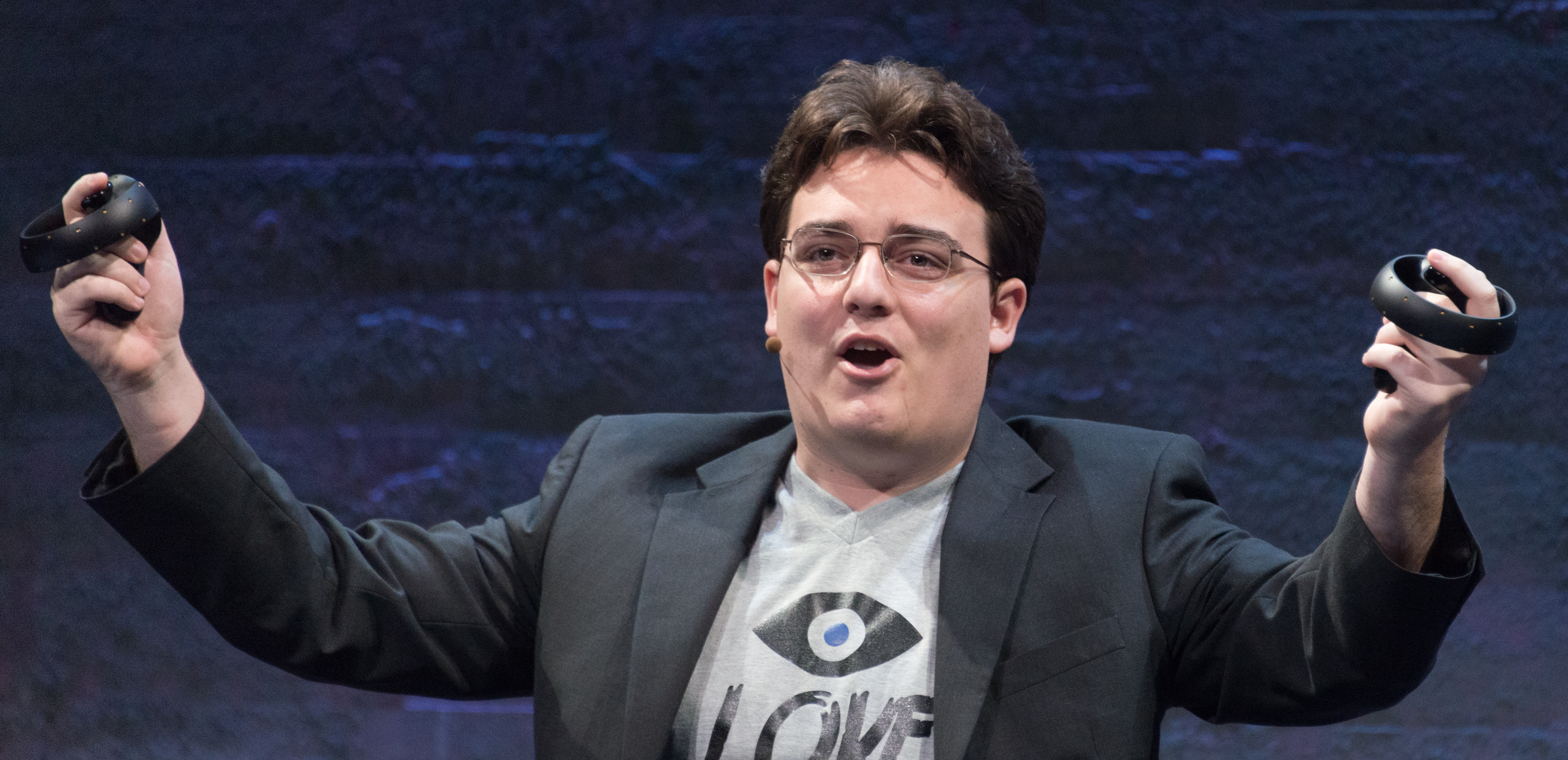 Palmer Luckey holds two Oculus Touch prototype controllers onstage in 2015