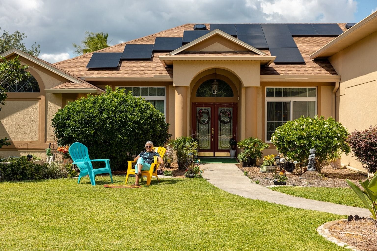 Homeowner relaxing in a lawn chair in front of a house with rooftop solar panels
