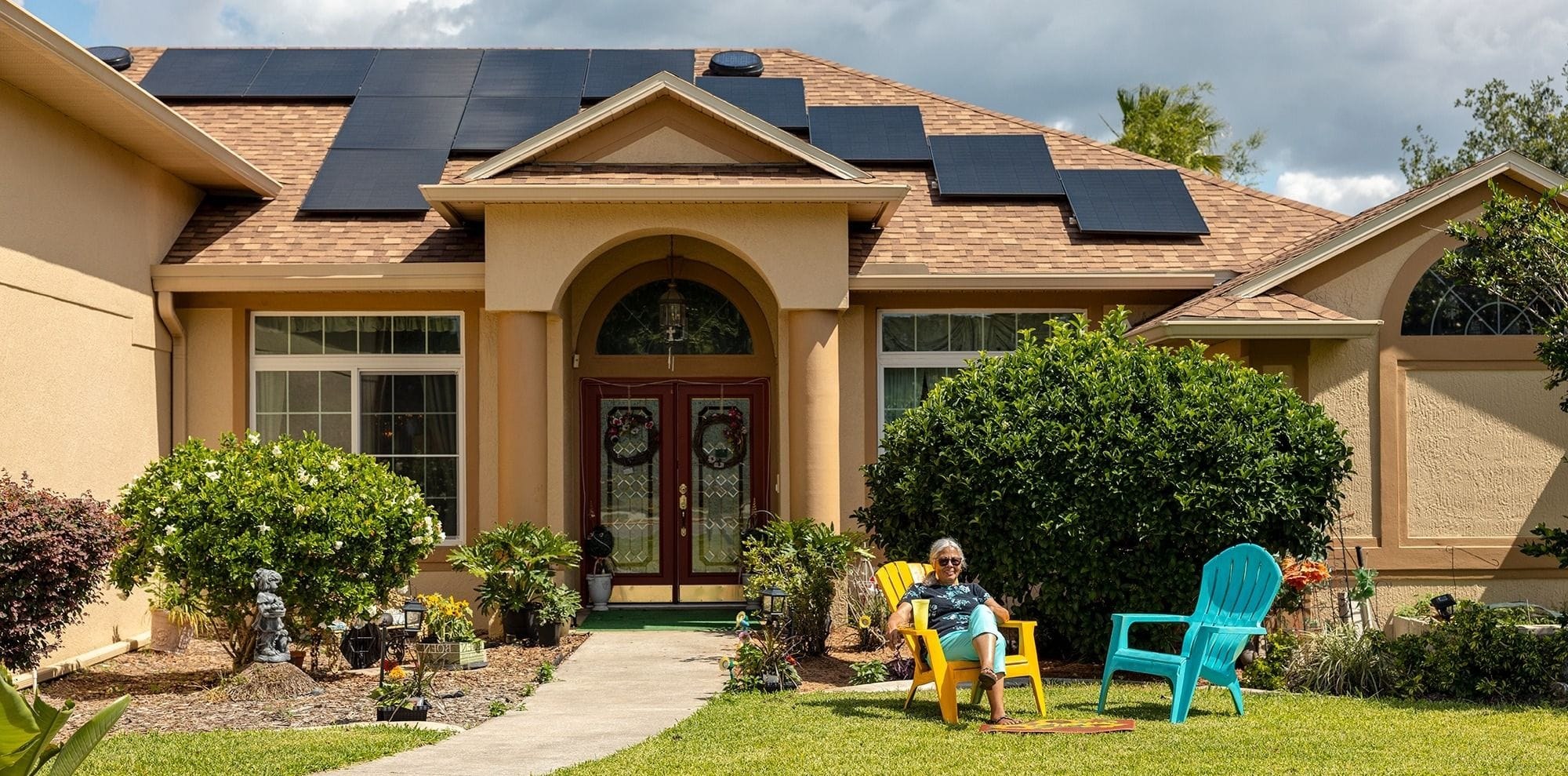 Suburban home with black solar panels installed across its roof on a bright day
