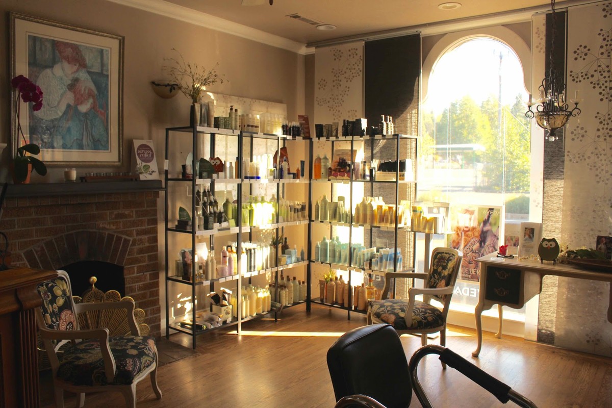 The sunlit Panache salon interior with a fireplace, floral chairs and shelves of Aveda products