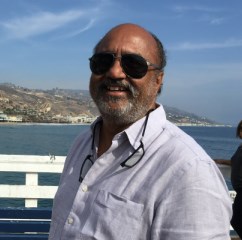 Par Chadha smiling outdoors beside the water, wearing sunglasses