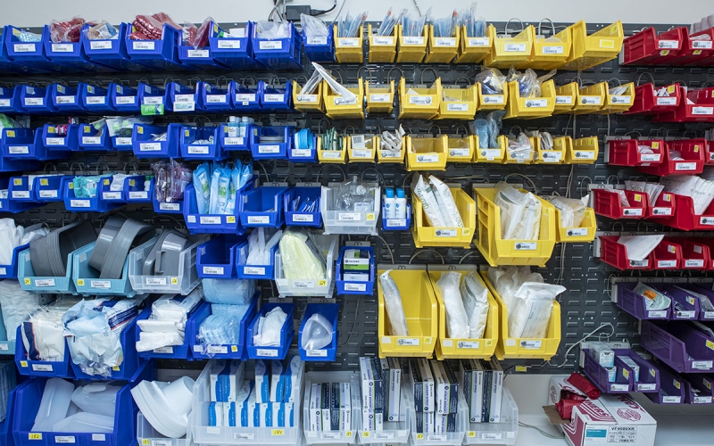 Rows of blue, yellow, red, and purple bins holding packaged medical supplies