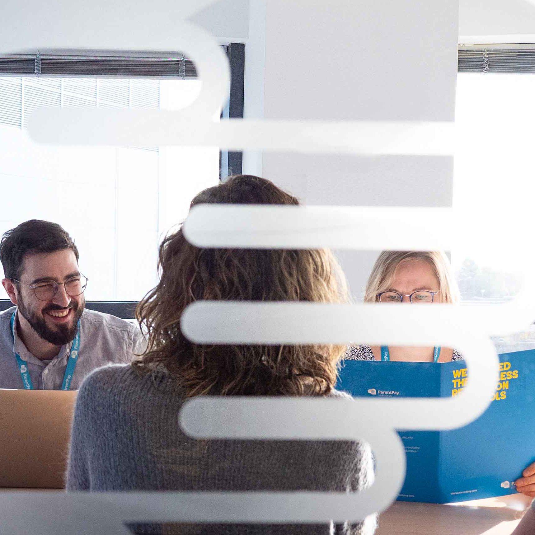 ParentPay colleagues meeting around a table behind frosted office glass