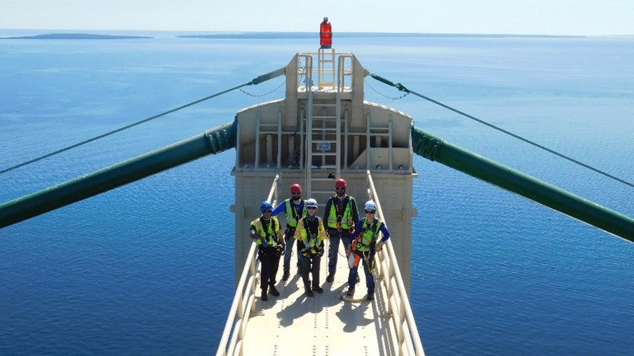 Parsons bridge team wearing safety harnesses high above the water on Mackinac Bridge