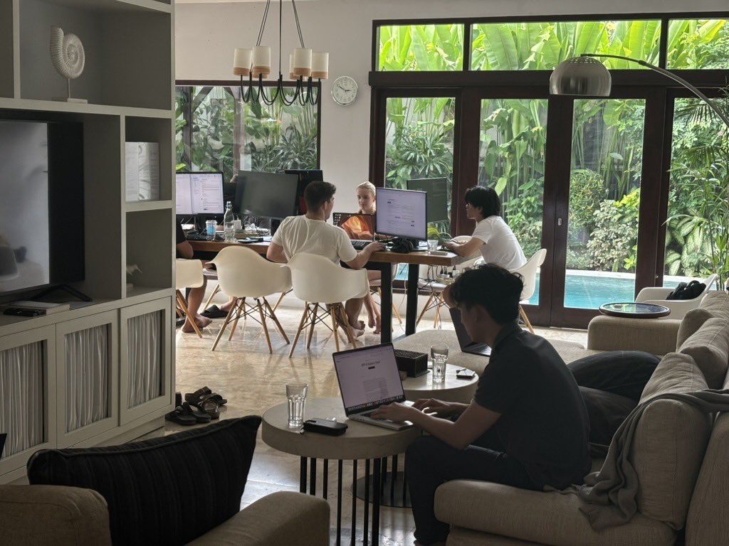 Members of the AfterQuery team working on laptops around a table and in a living room during a public team retreat