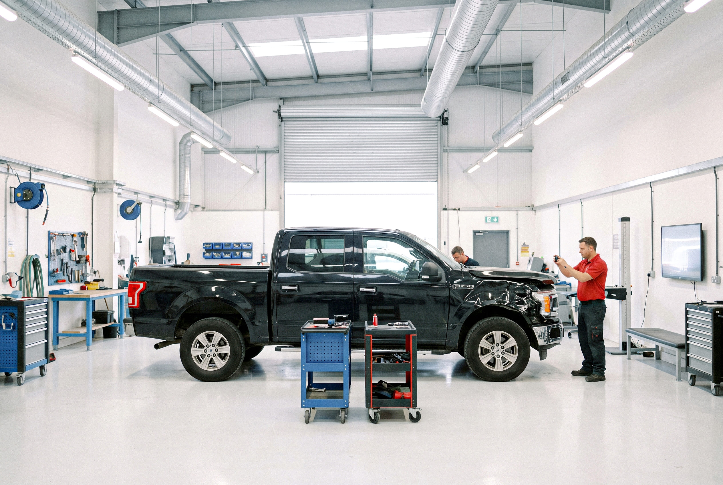 A technician photographing a vehicle in a repair bay