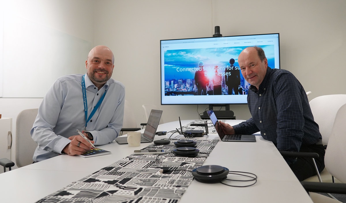 Pasi Leipala, left, and Jyrki Okkonen at a table signing the Empathic Building acquisition papers