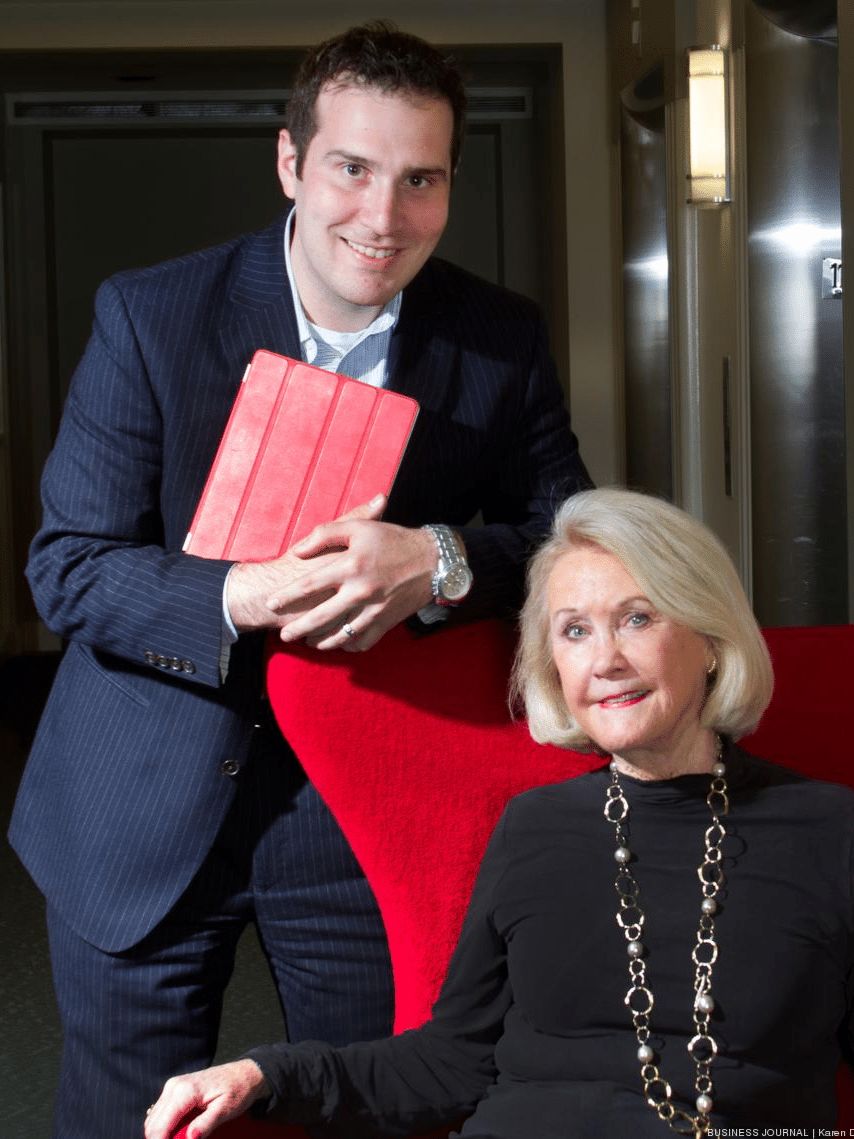 Aaron Blank standing beside Pat Fearey, who is seated in a red chair