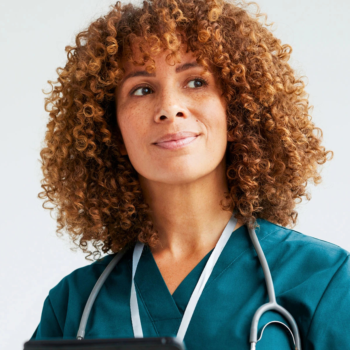 Healthcare professional in teal scrubs holding a digital tablet
