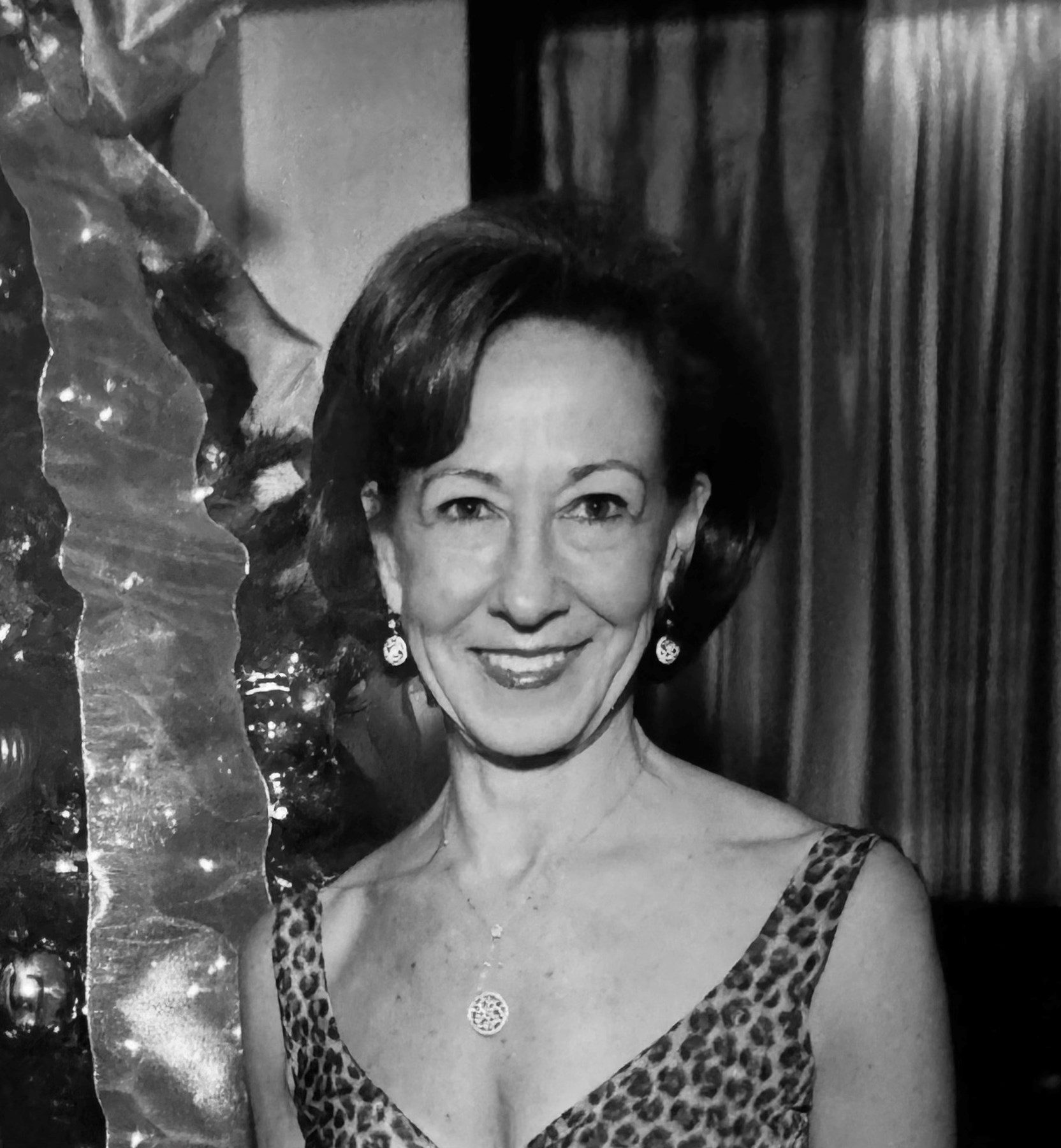 Patti Cook smiling beside festive decorations in a black-and-white personal photograph