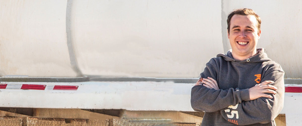 Patrick Malley smiling beside a Rolfson Oil trailer in a company sweatshirt