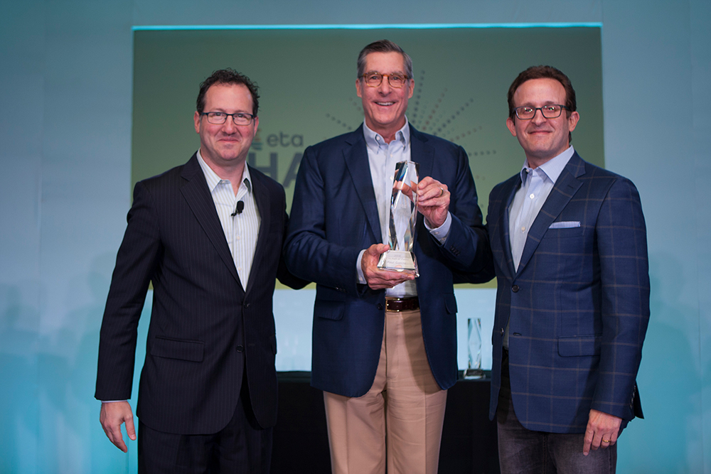 Paul R. Garcia holds his ETA Hall of Fame award between Jason Oxman and Jeff Sloan in 2018