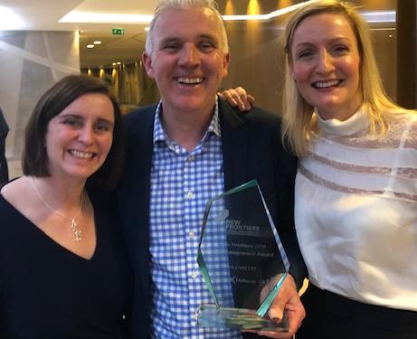 Paul McCarthy holding his New Frontiers award between two fellow attendees at the 2020 showcase.
