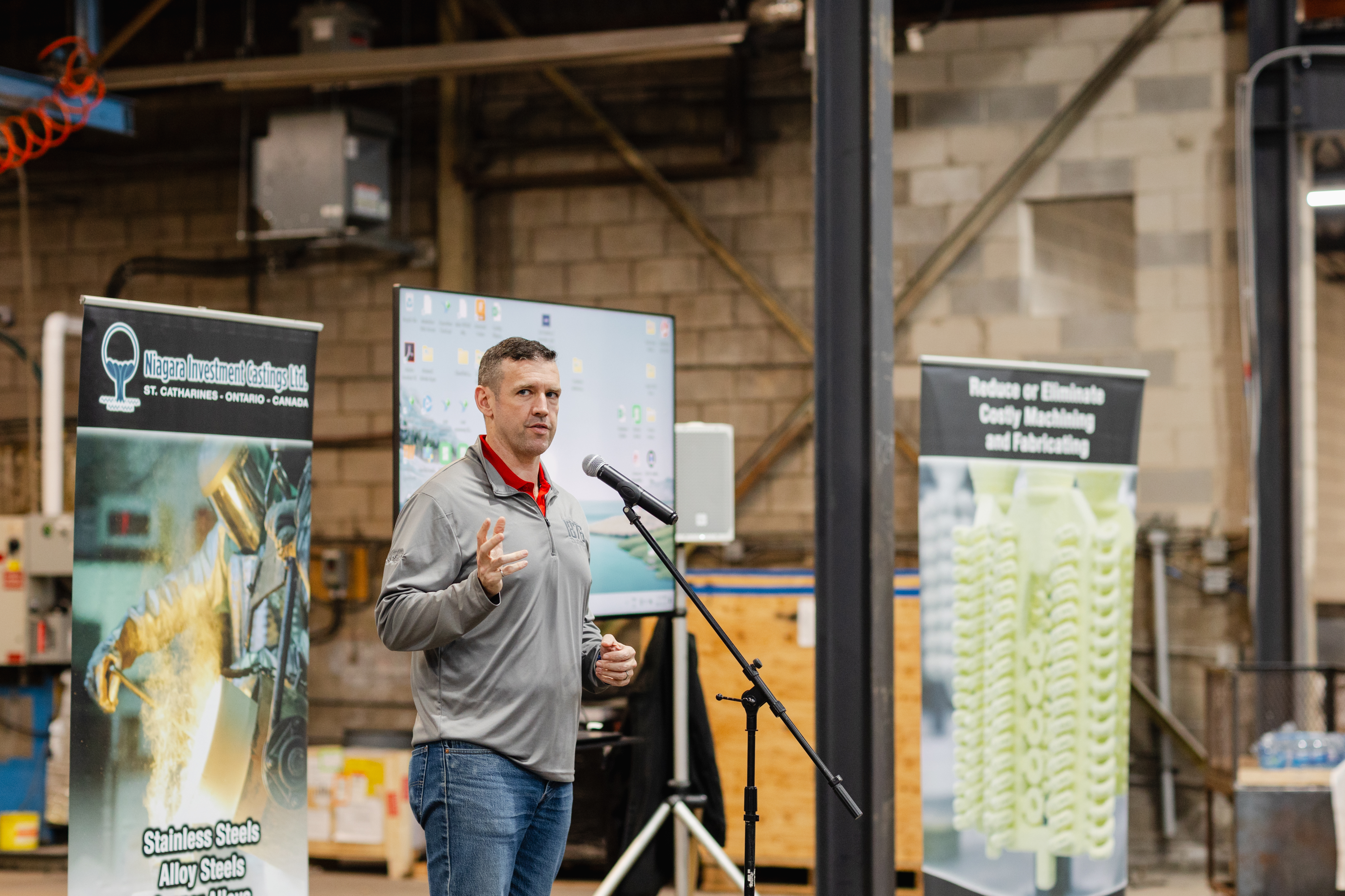 Paul Tuzi speaking into a microphone inside Niagara Investment Castings at its reopening celebration