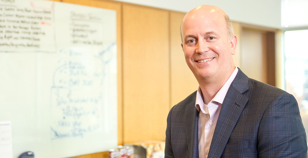 Paul Wagstaff smiling in an office with a whiteboard behind him