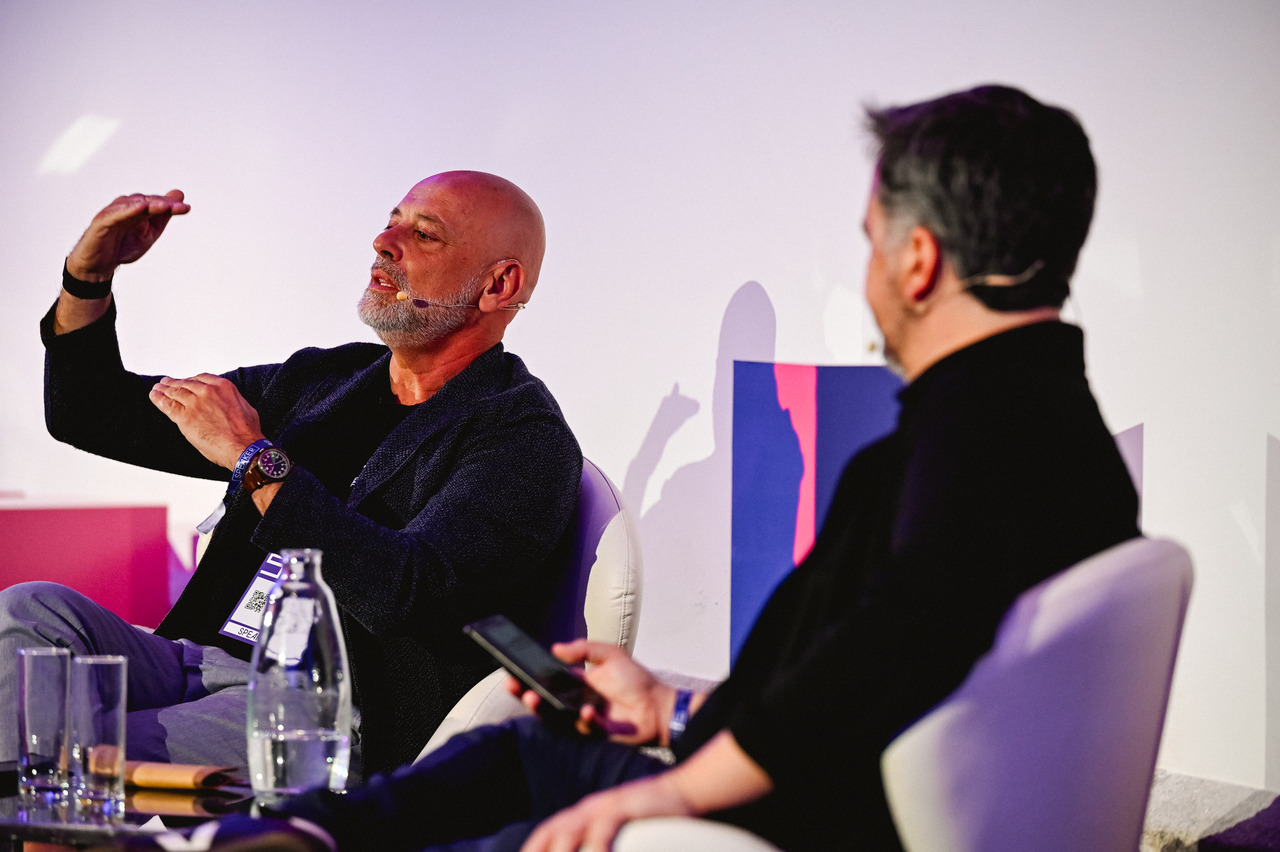 Paulo Rosado gesturing during a seated discussion at SIM Conference in Porto