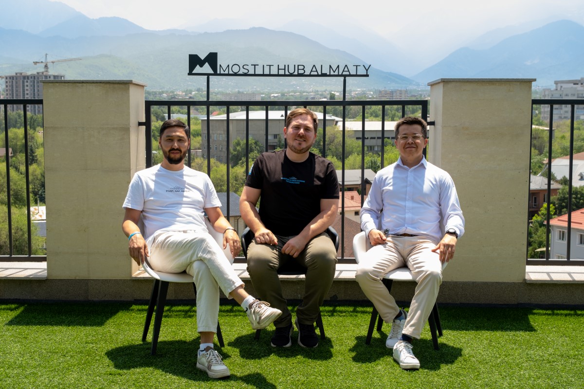 Mirat Akhmetsadykov, Pavel Koktyshev and Alim Khamitov seated together at MOST IT Hub in Almaty, with mountains behind them