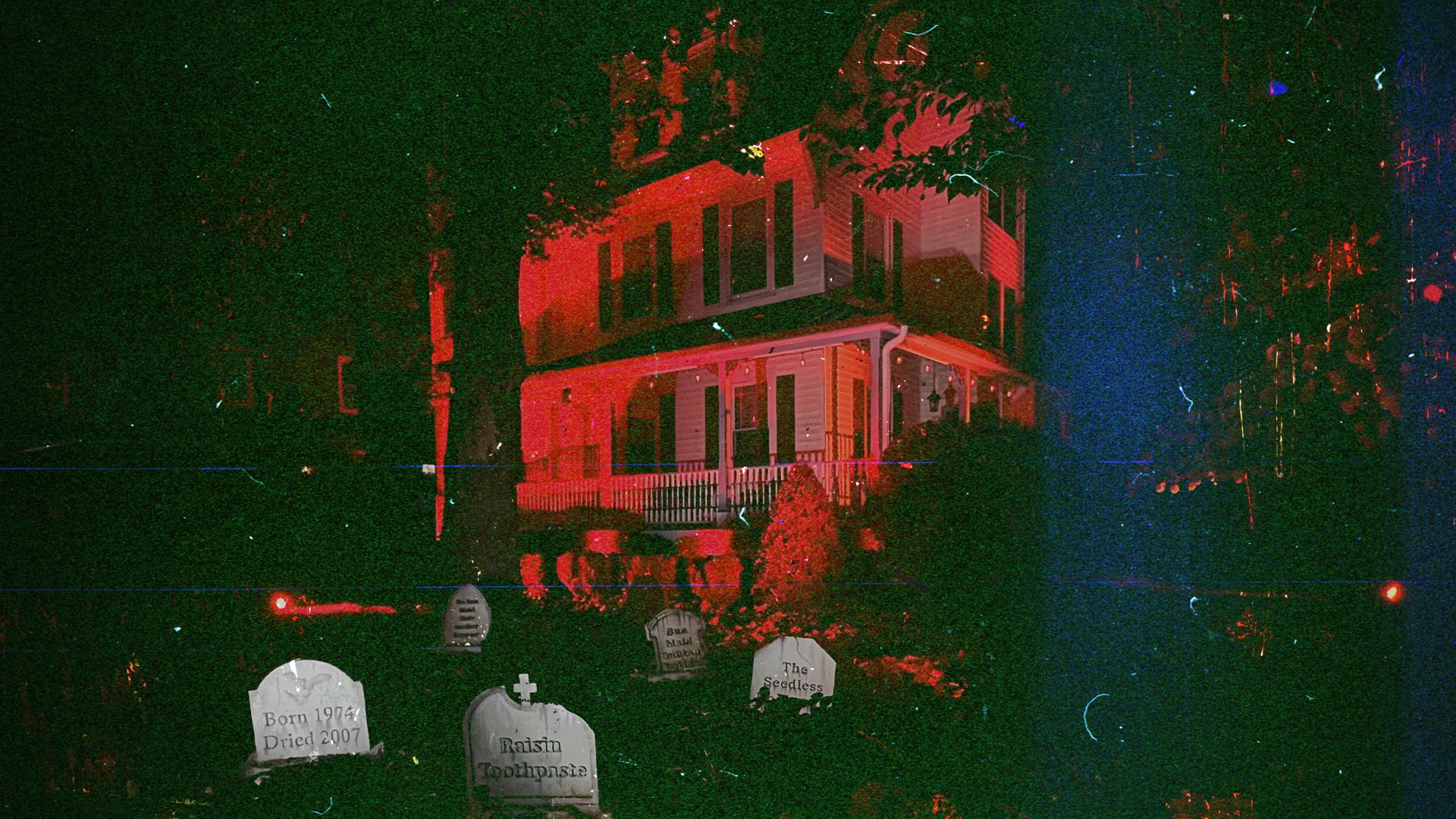 The Sun-Maid Raisin House lit in red at night, with raisin-themed gravestones on the lawn