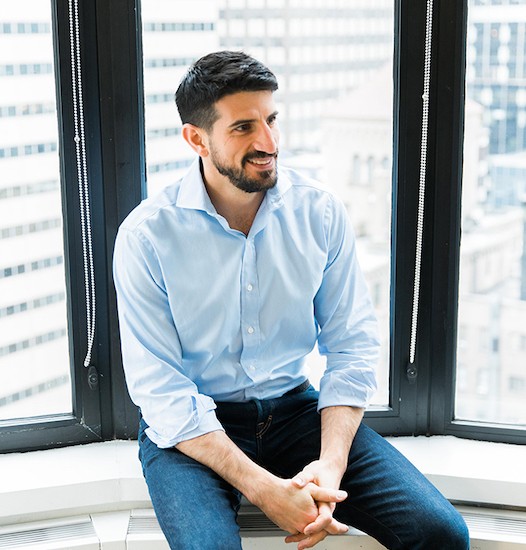 Paxos co-founder and CEO Charles Cascarilla seated beside office windows