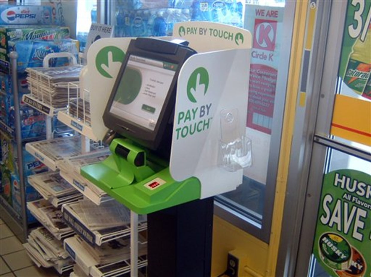 A green and white Pay By Touch enrollment kiosk inside a convenience store