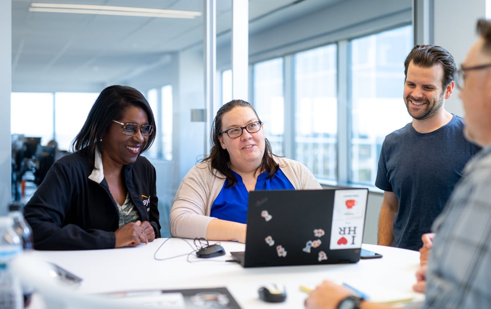 Paylocity employees collaborating around a laptop in their office