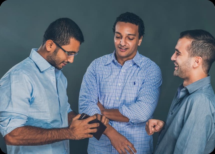 Paymob's three co-founders gathered around a phone