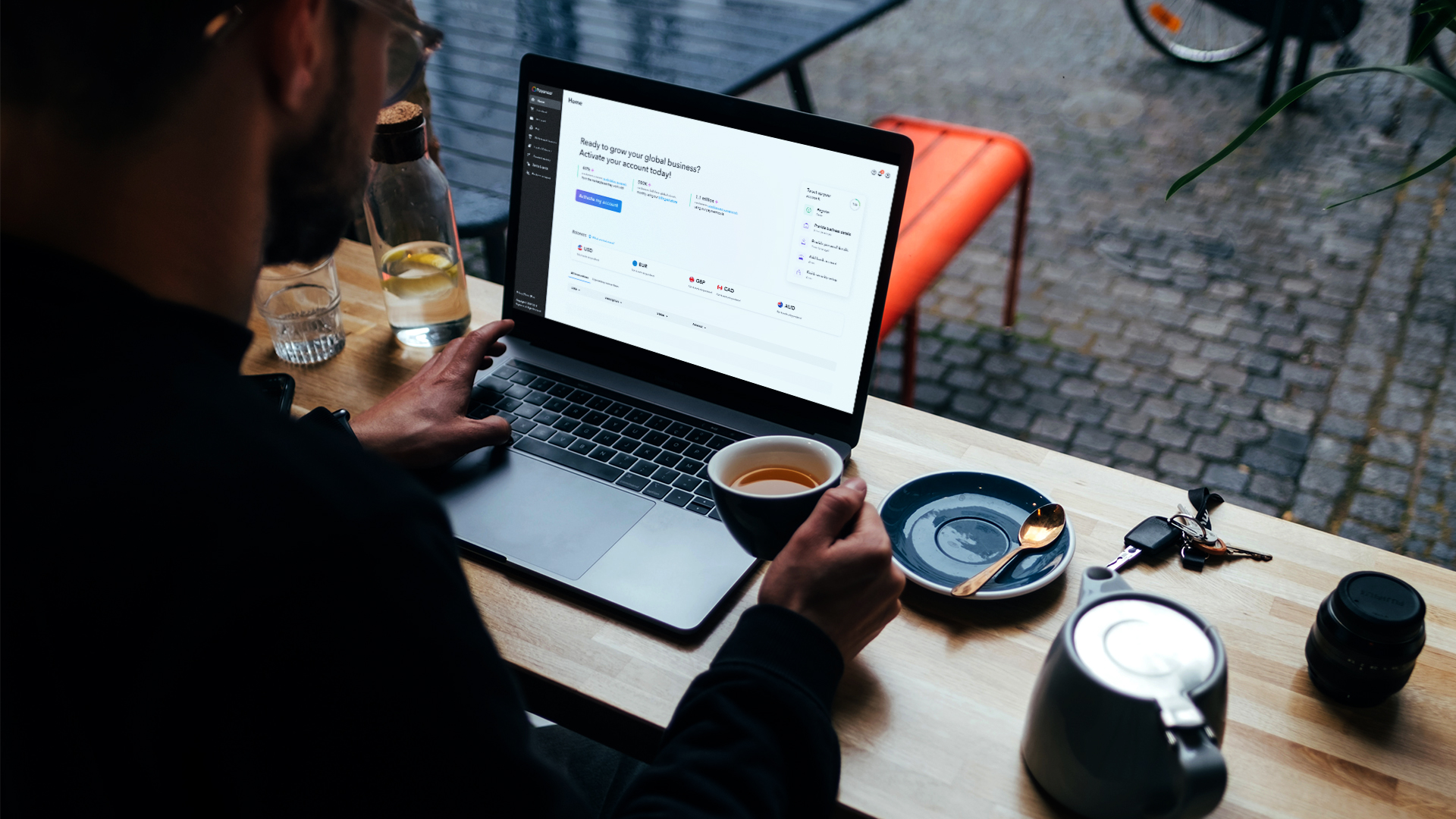 Payoneer’s business account interface open on a laptop beside a cup of coffee