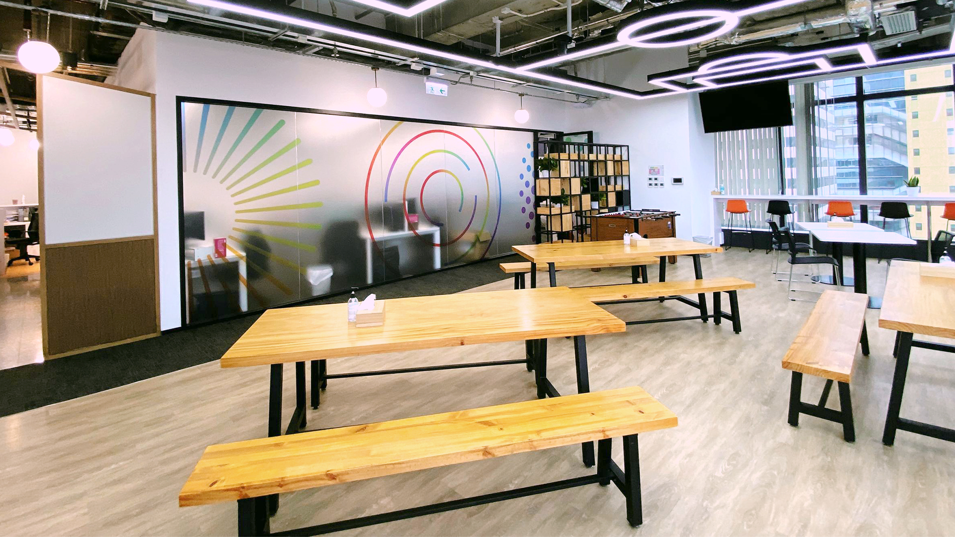 An open communal area in a Payoneer office with tables and colorful wall graphics
