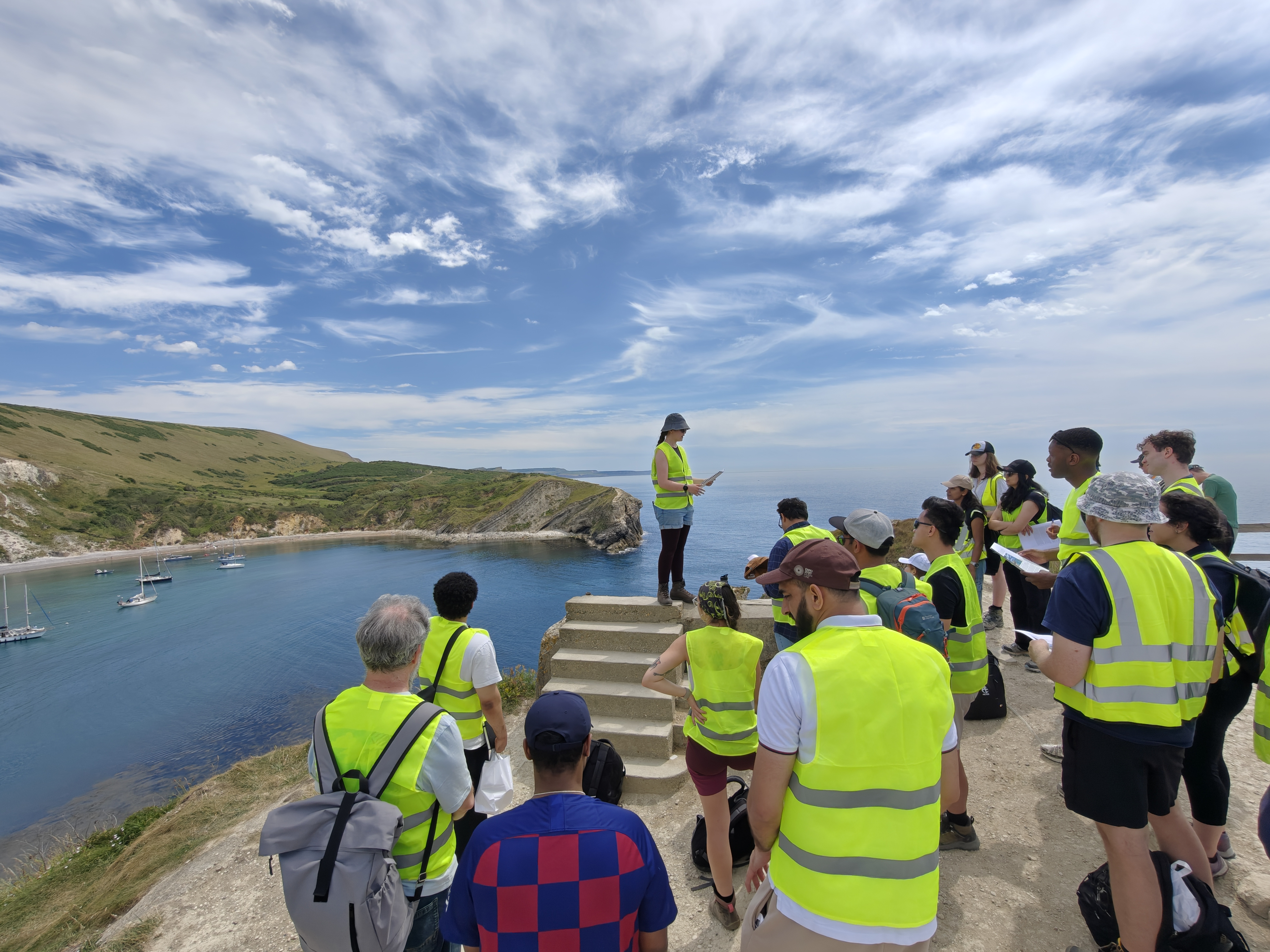 PETEX colleagues in high-visibility jackets studying coastal geology above Lulworth Cove