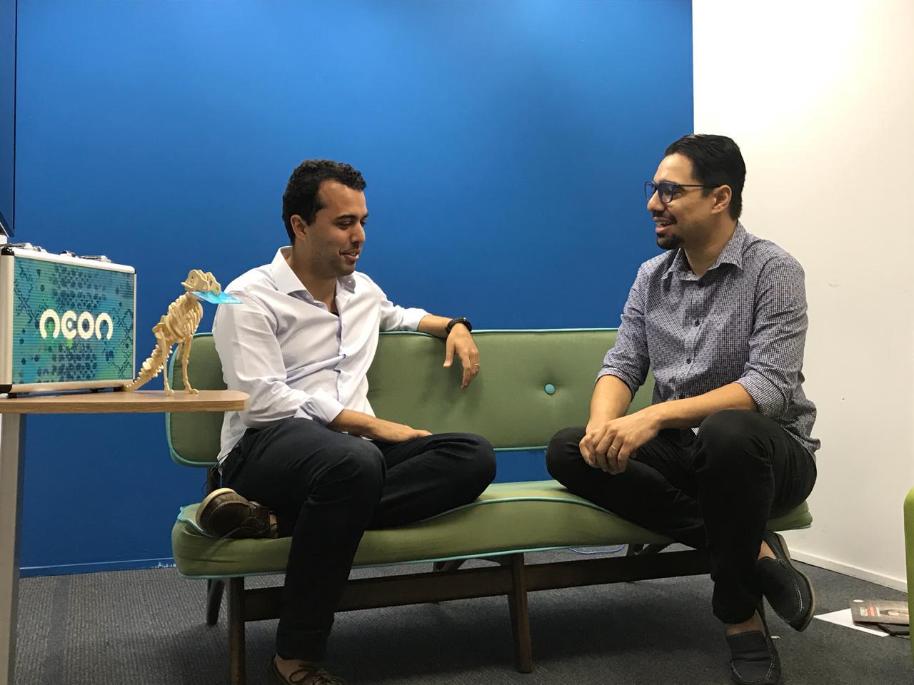Pedro Conrade, left, seated on a green sofa during an interview at Neon