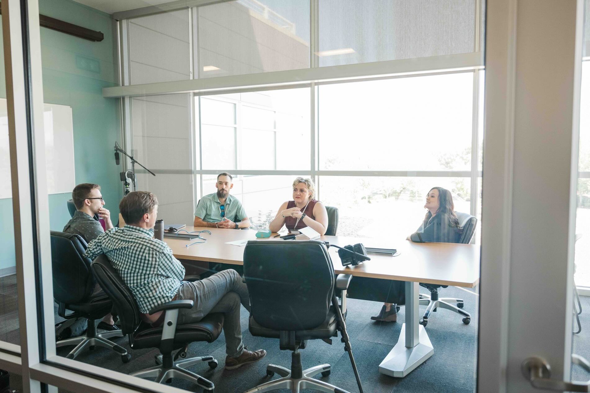 Pennant Service Center colleagues talking around a meeting table in a glass-walled room