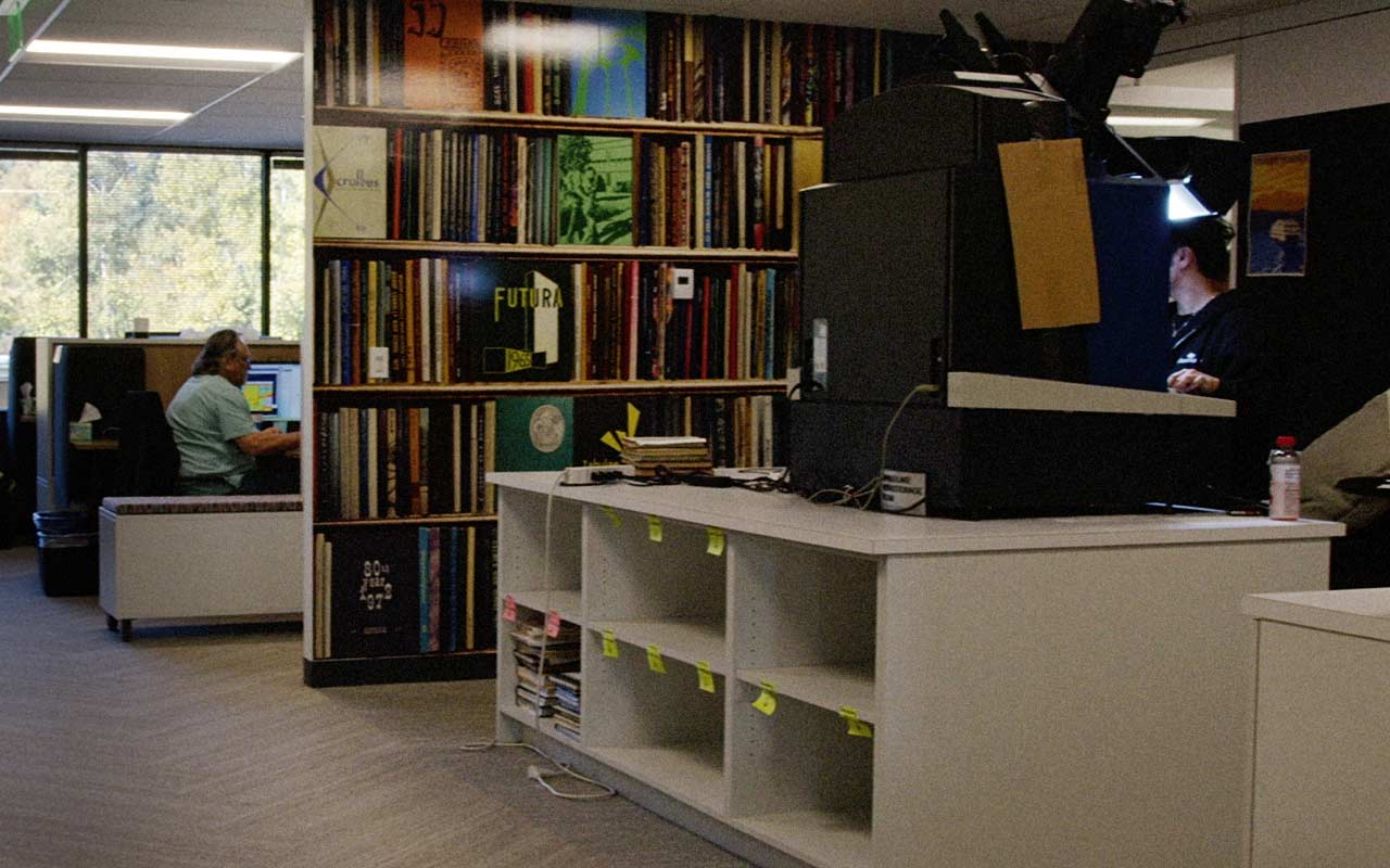 Shelves of yearbooks beside workstations and imaging equipment in a PeopleConnect archive office