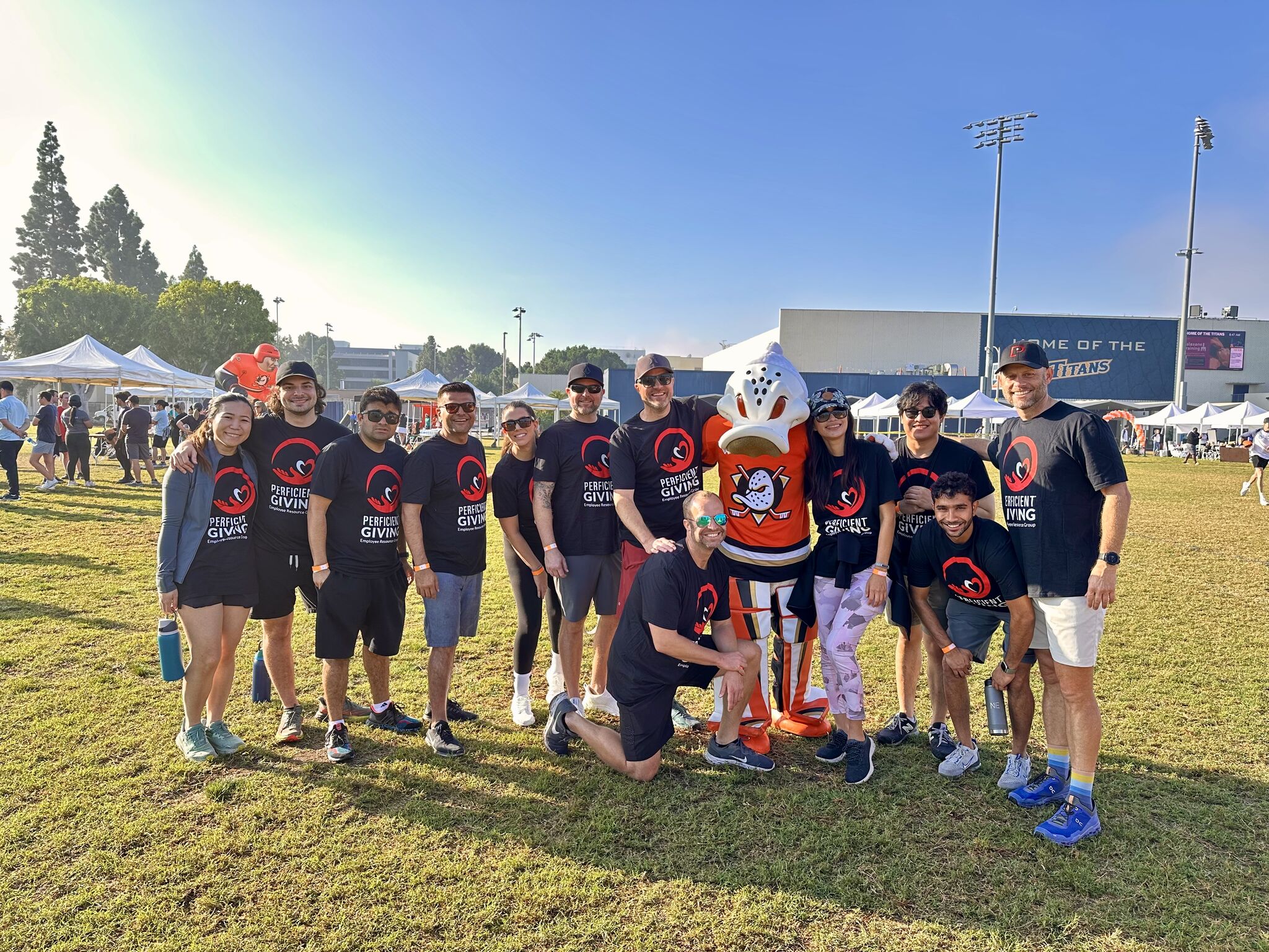 Perficient Giving colleagues gather outdoors with a hockey mascot at a Southern California event