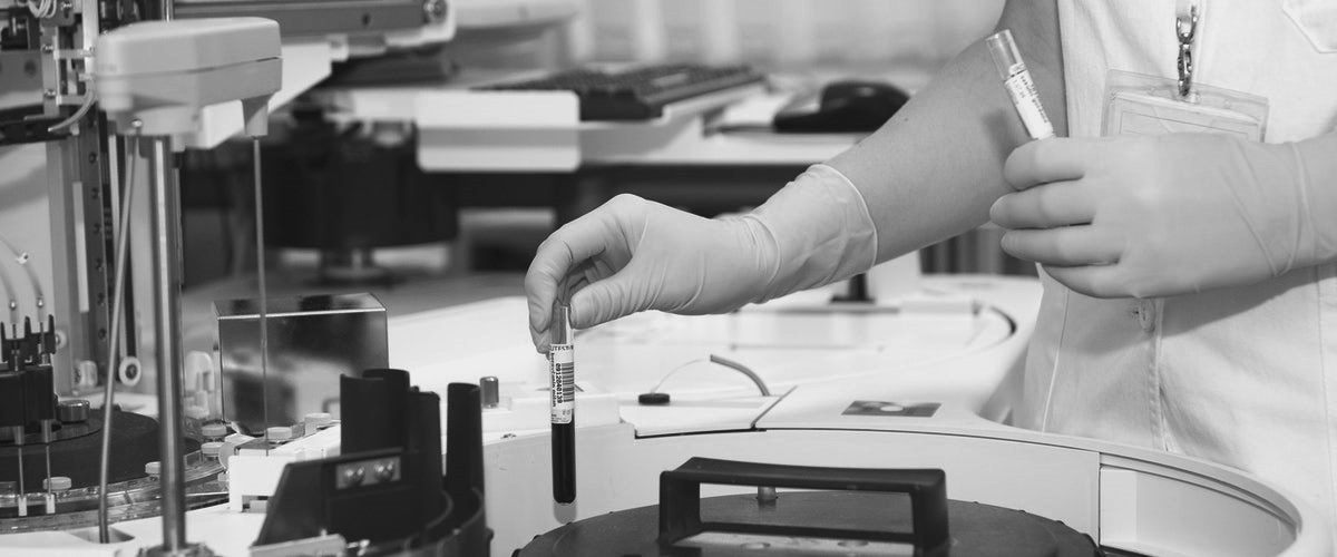 A laboratory technician handling a sample beside analysis equipment