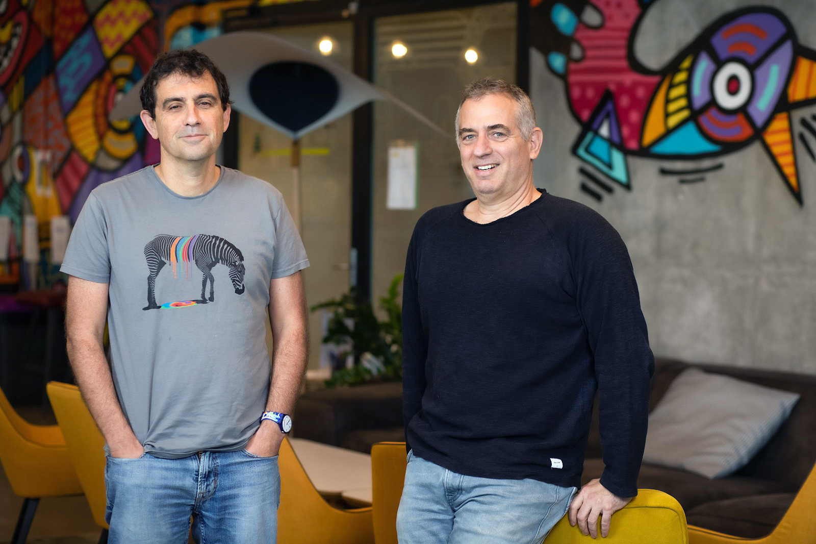 Personetics co-founders David Sosna and David Govrin seated in a colorful office lounge