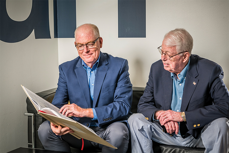 Pete Barr Jr., left, and his father Pete Barr Sr. looking through newspaper clips at their Orlando office
