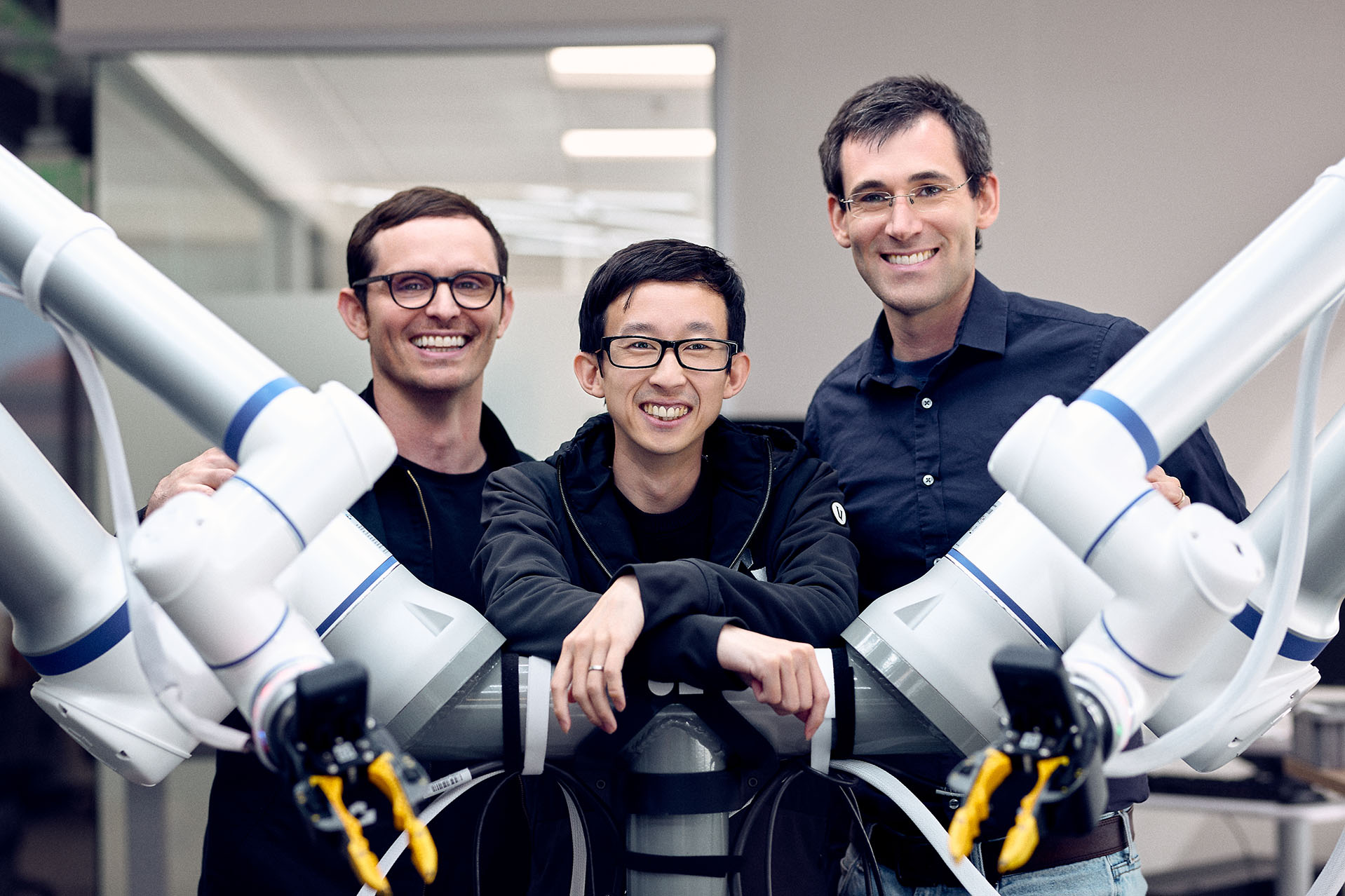 Pete Florence, left, with Generalist co-founders Andy Zeng and Andrew Barry between robot arms