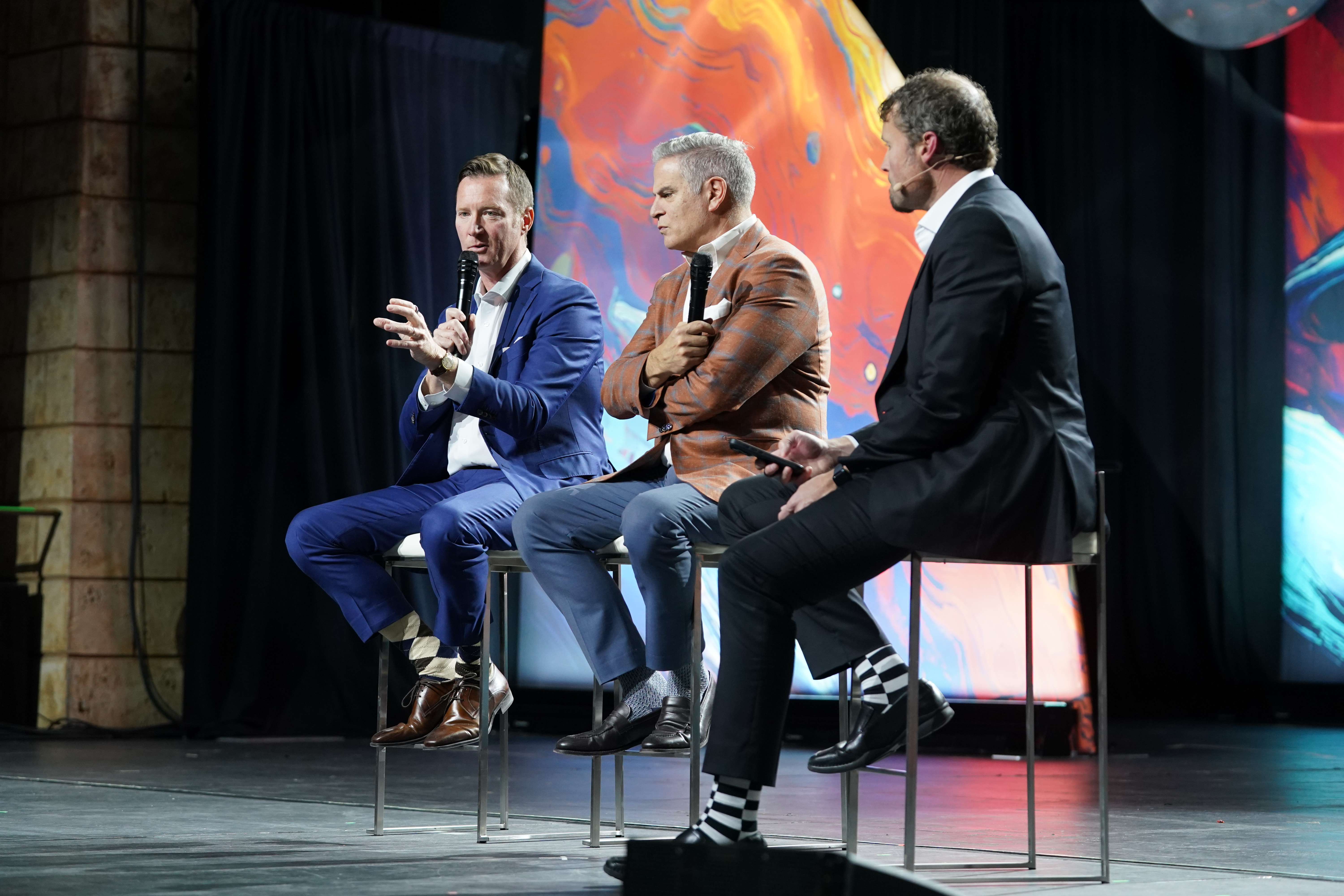 Pete Stoy, seated at left, speaking during a three-person leadership discussion at Hanger LIVE