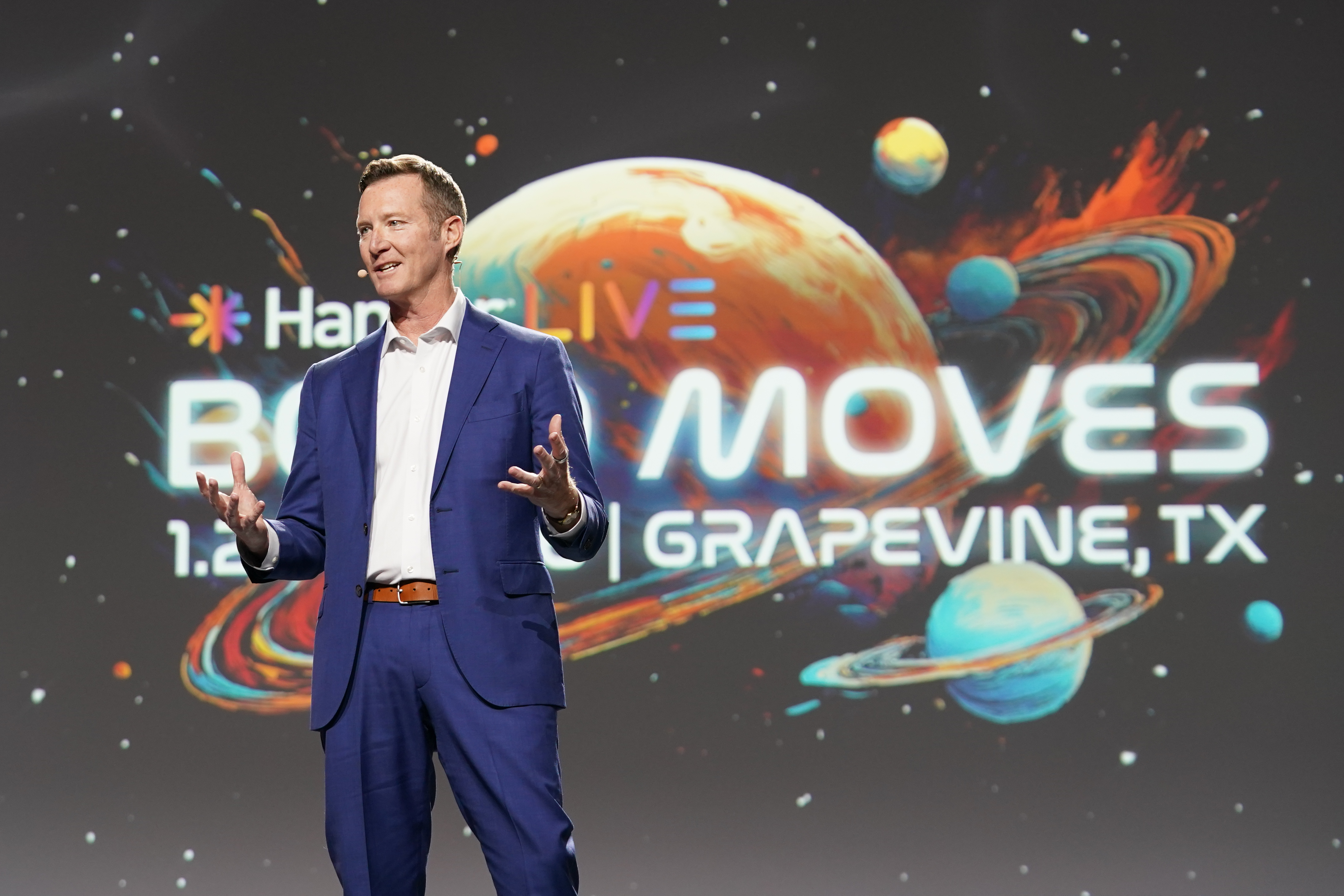 Pete Stoy speaking onstage in a blue suit at Hanger LIVE 2026