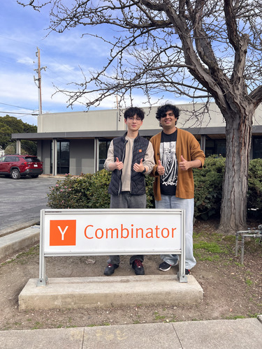 Peter Bai and Muhammad Awan standing behind a Y Combinator sign outdoors