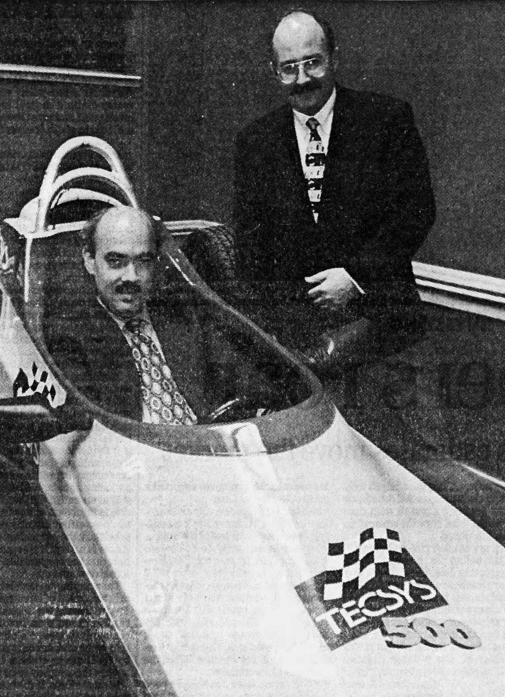 Archival black-and-white photograph of Peter and Dave Brereton with a racing car