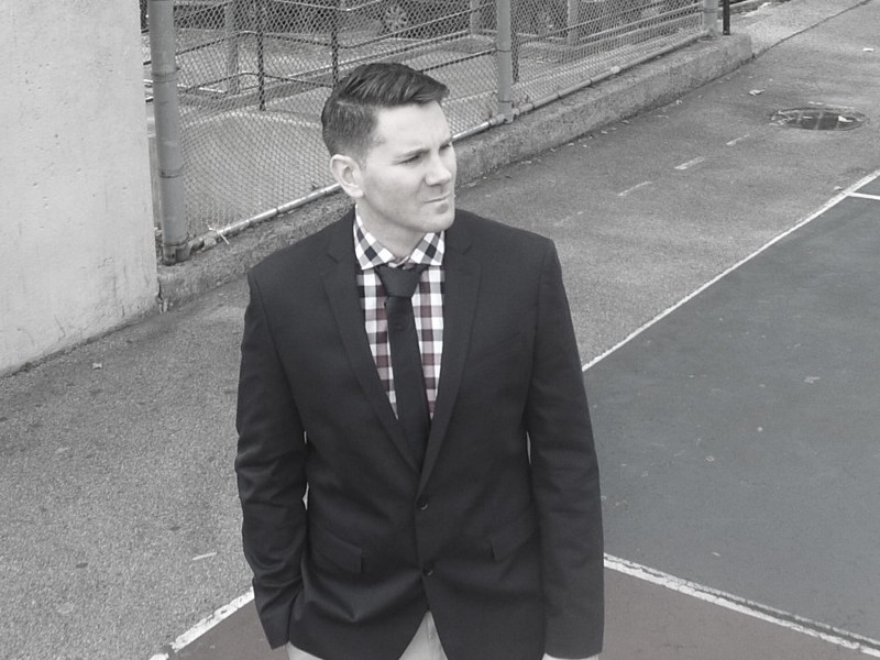 Peter Robert Casey in a suit beside an outdoor basketball court